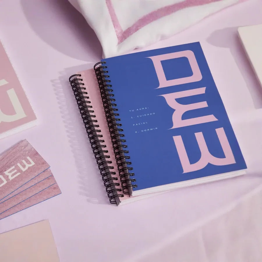 Spiral-bound notebook with blue cover featuring white text on a light pink background